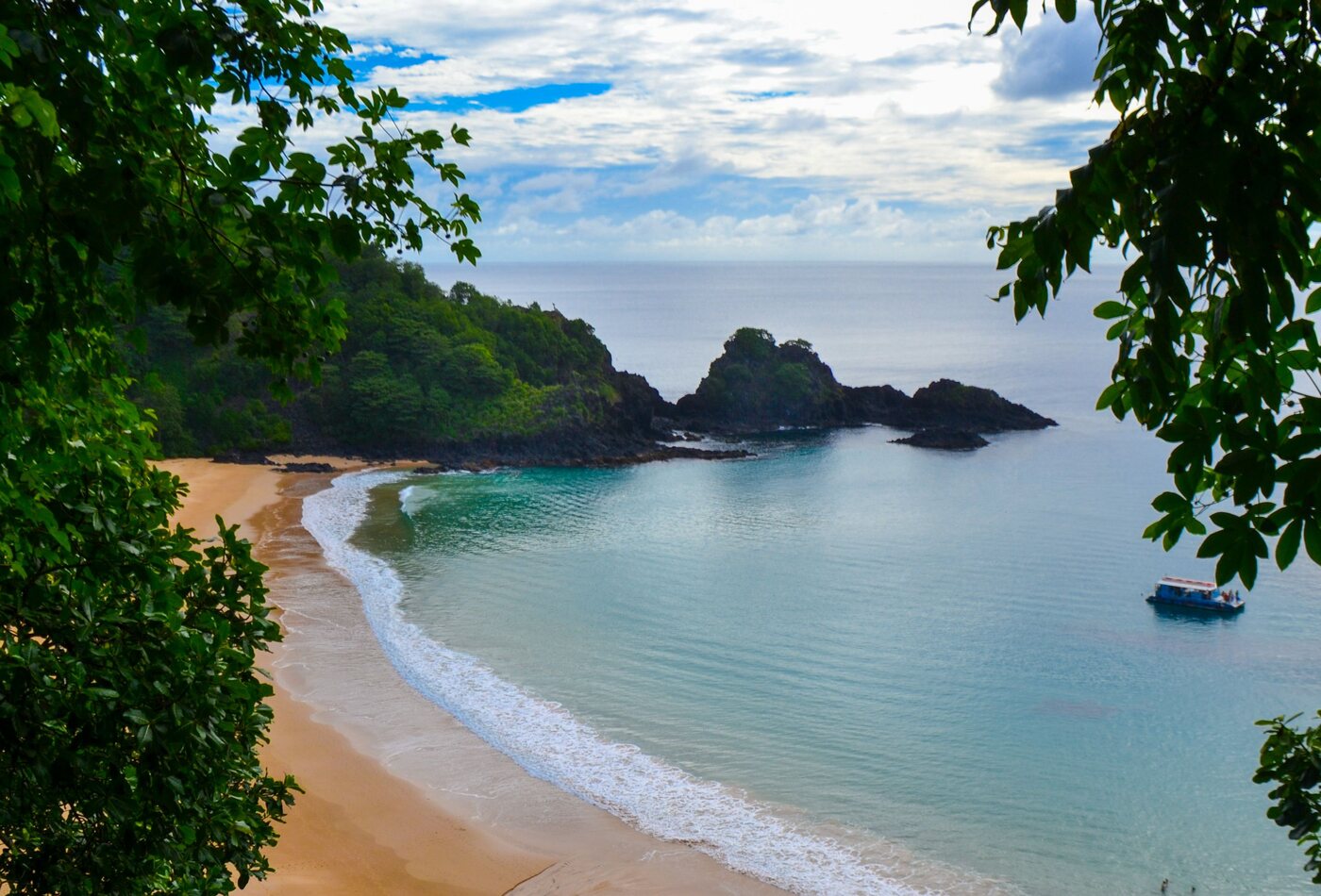 Enseada de areia clara vista entre as &aacute;rvores em Fernando de Noronha