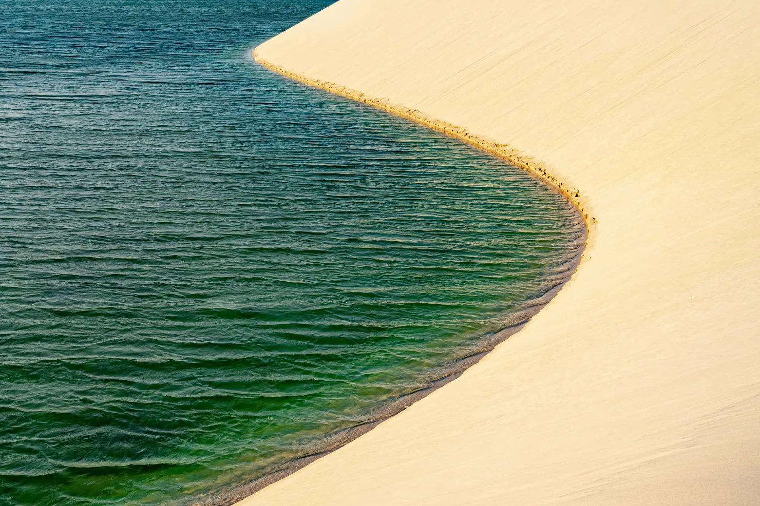 Lagoa de água turquesa formada entre as dunas dos Lençóis Maranhenses