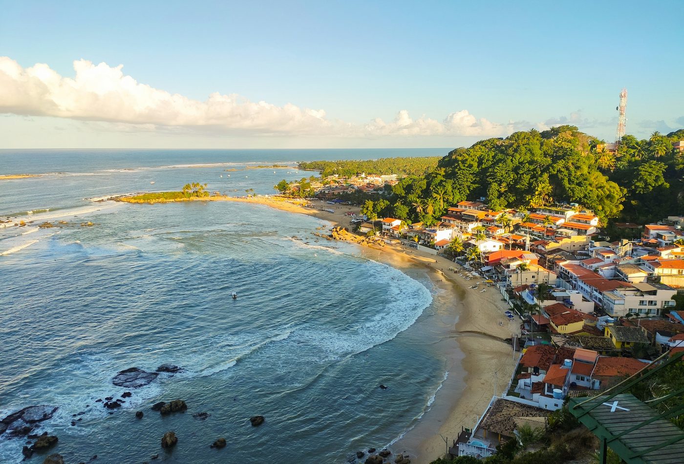 Vista aérea da vila de Morro de São Paulo no fim da tarde, com os telhados vermelhos junto à praia