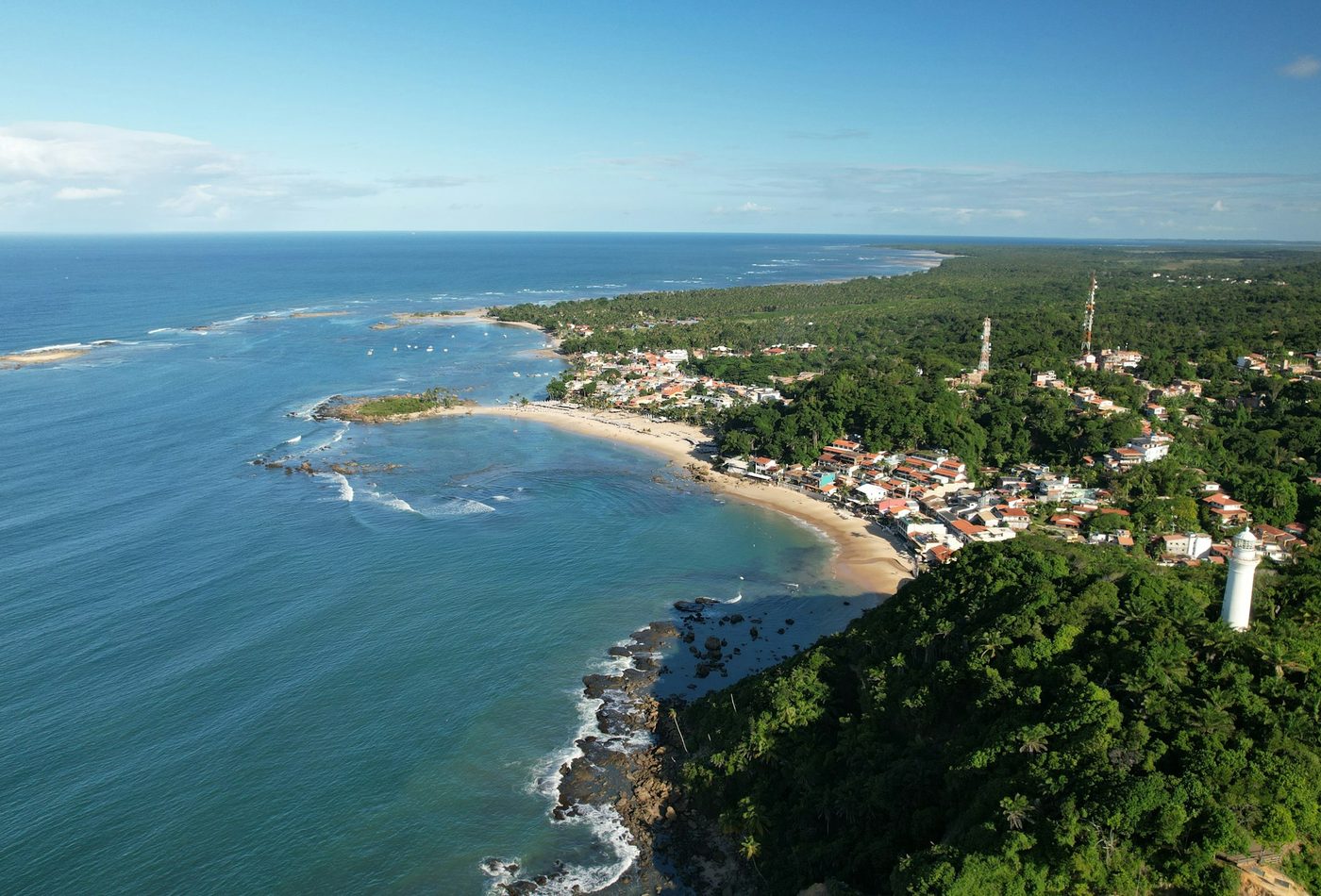 Vista aérea de Morro de São Paulo mostrando a vila, a praia e a torre branca do farol no alto do morro
