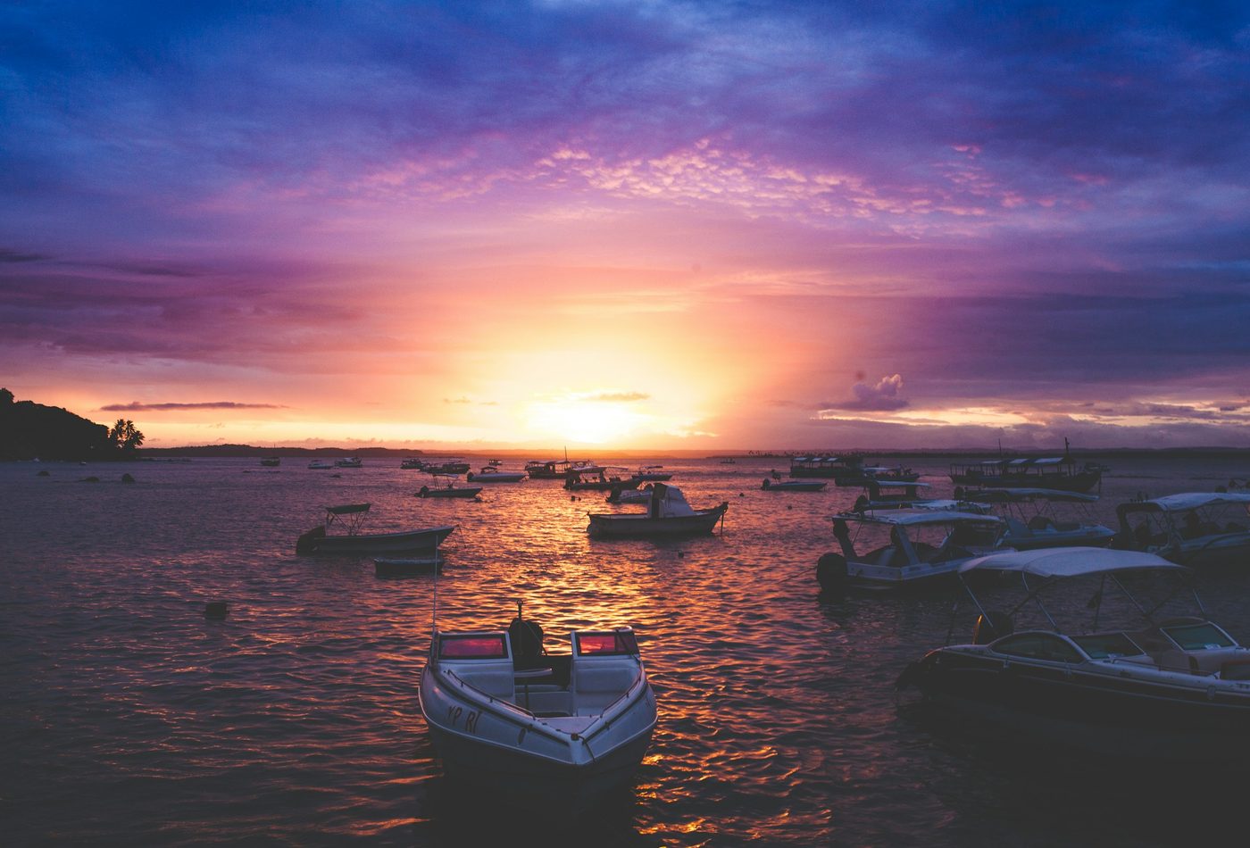 Pôr do sol alaranjado sobre o mar com barcos ancorados em Morro de São Paulo