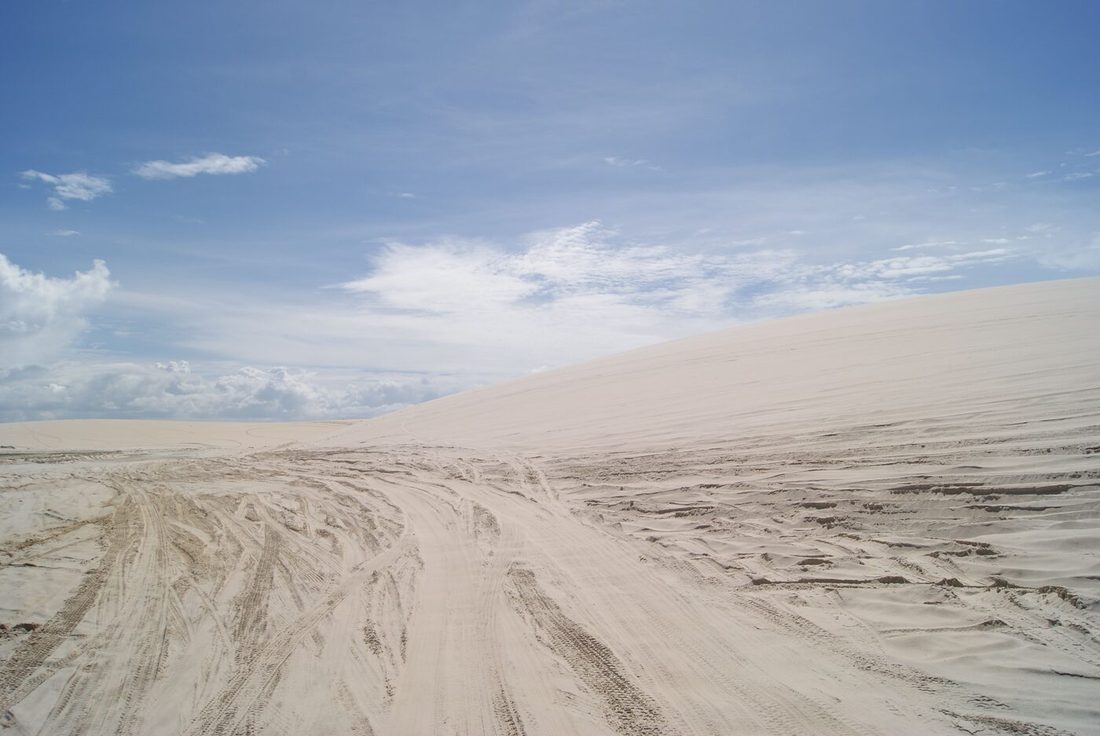 Marcas de pneu sobre a areia batida de um trecho costeiro