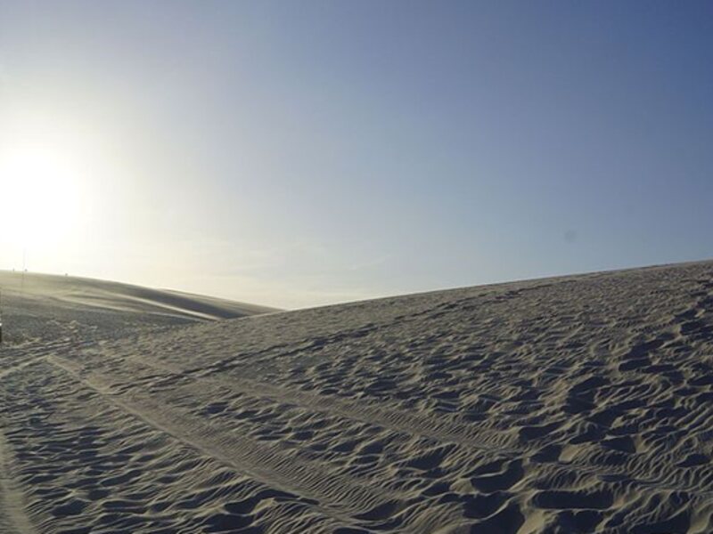 Nascer do sol e veículo 4x4 nas dunas dos Lençóis